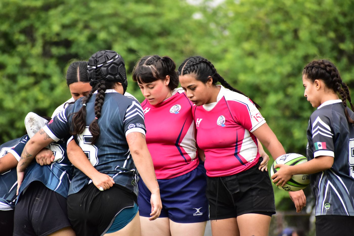 Jugadoras de la Legión forman un scrum frente a un equipo de rosa